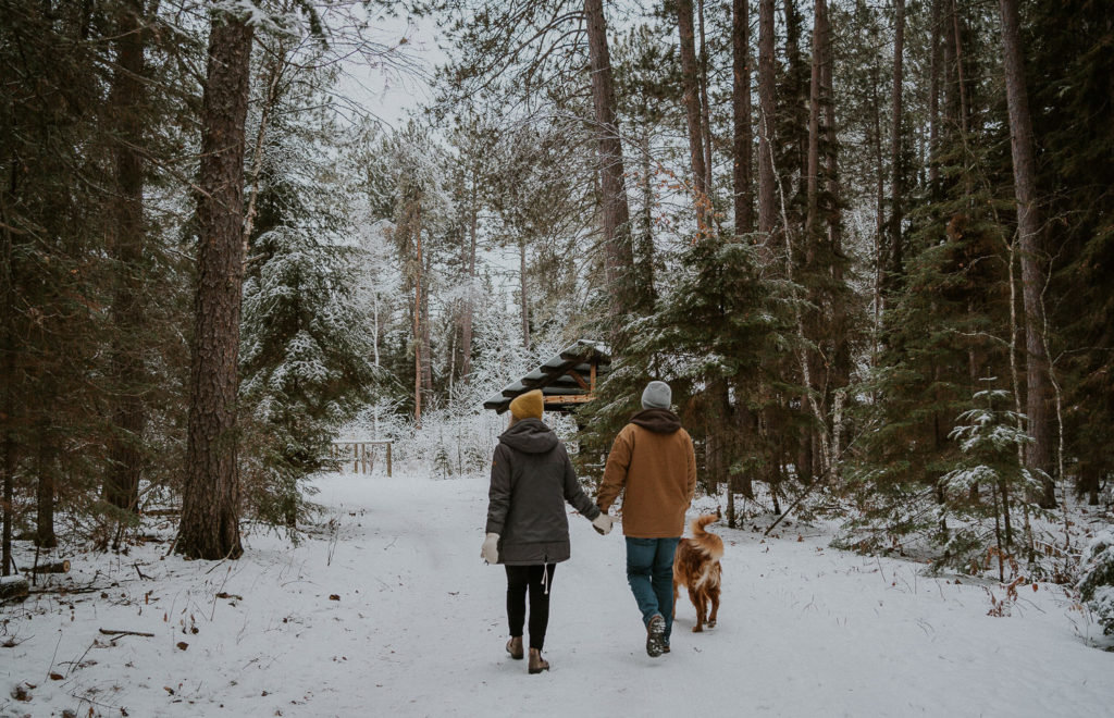 Couple holding hands walking down a winter trail