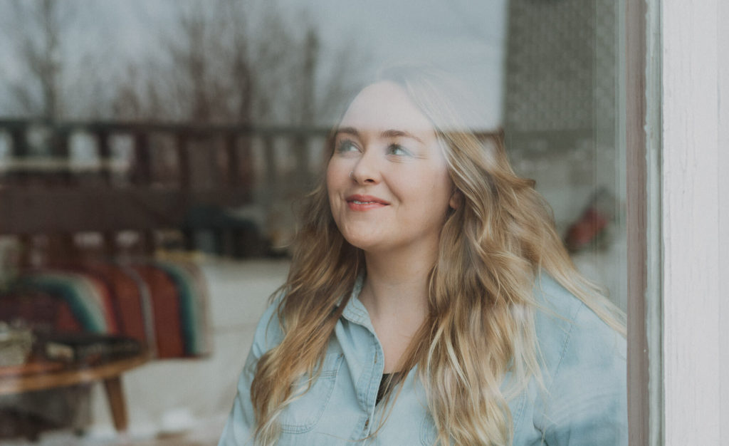 Young blonde woman looking out the window